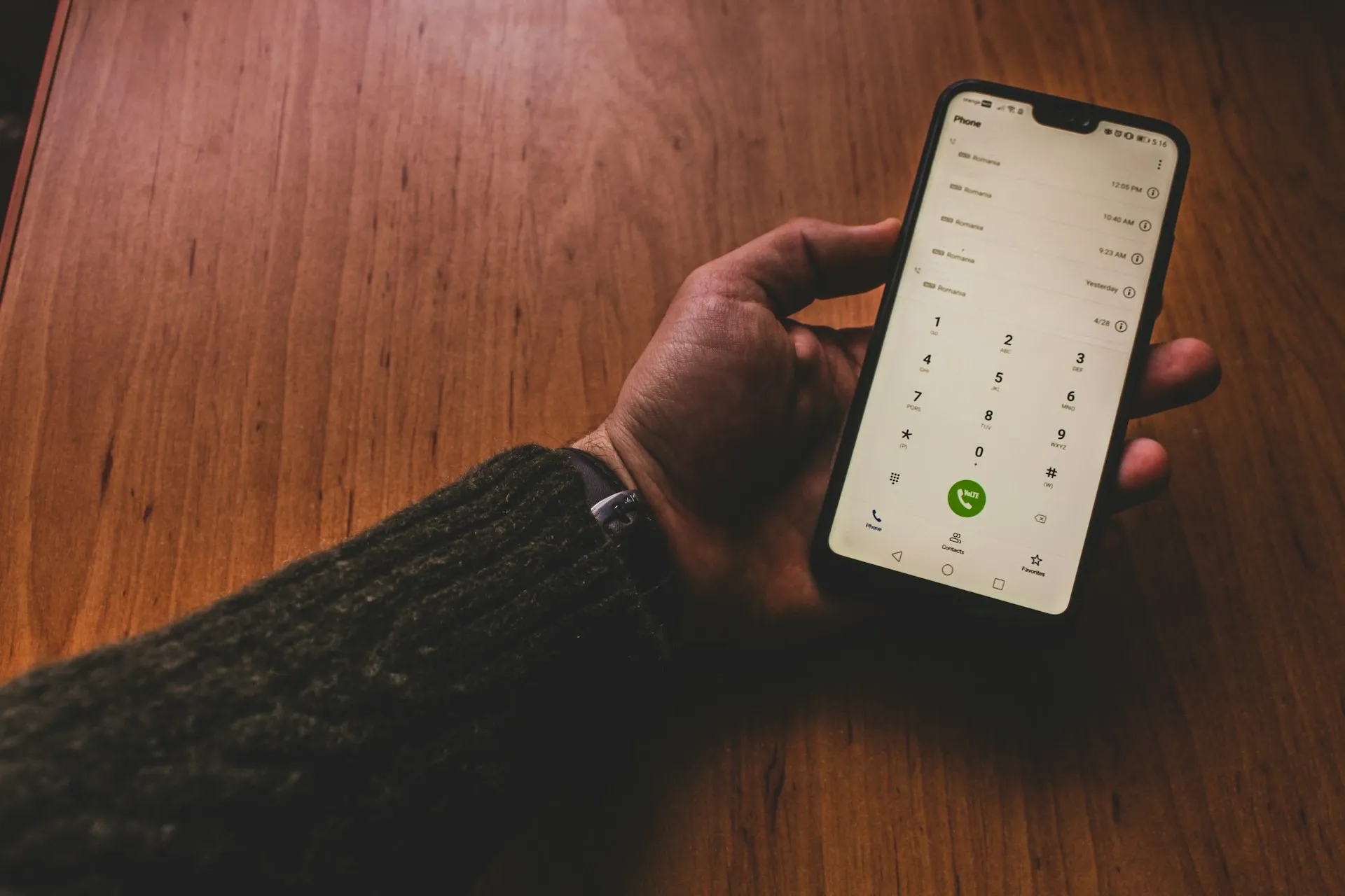 A person holding a smartphone with a green call button