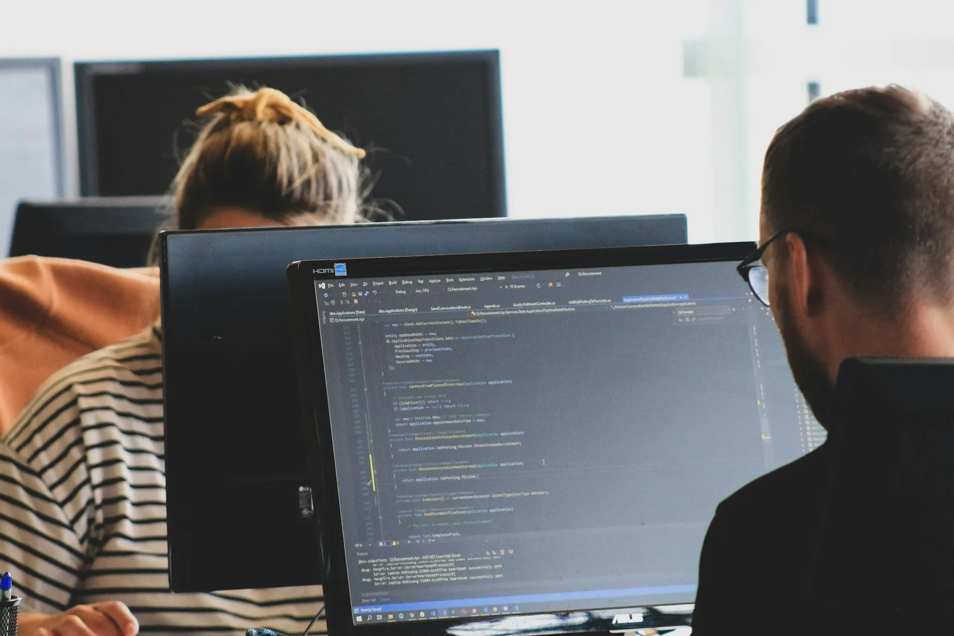 A woman seated in front of a computer monitor in a modern workspace