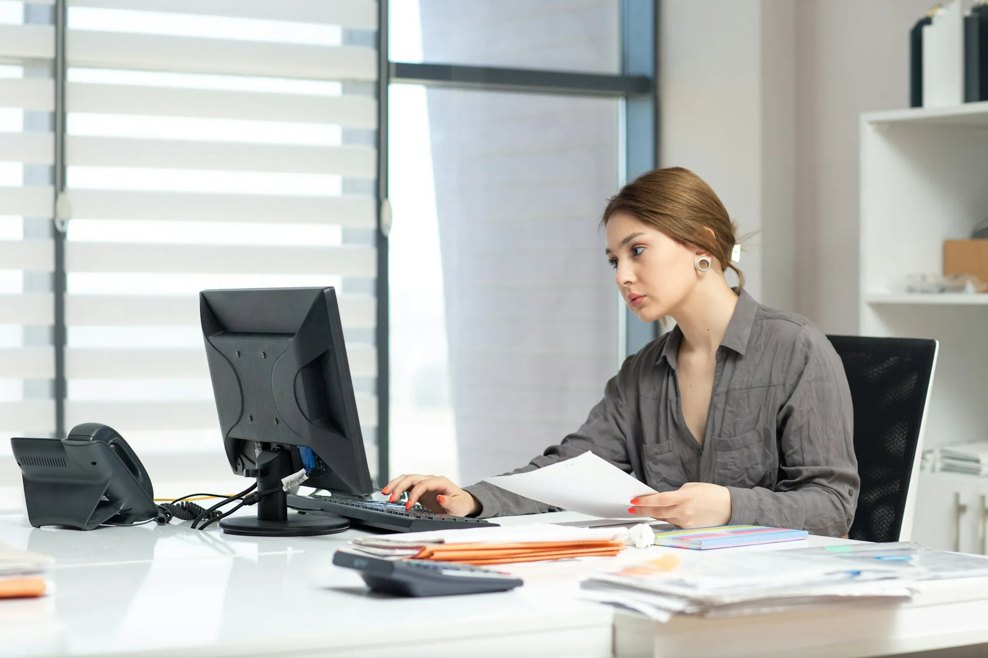 Sales professional reviewing documents and managing business tasks at a computer