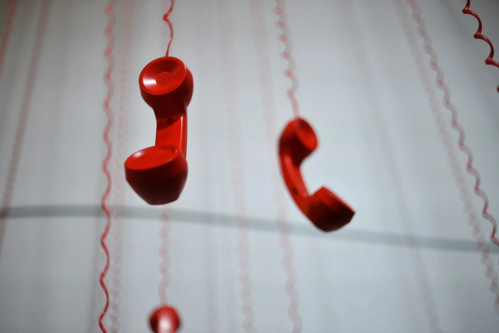 Red vintage phone handsets suspended from above