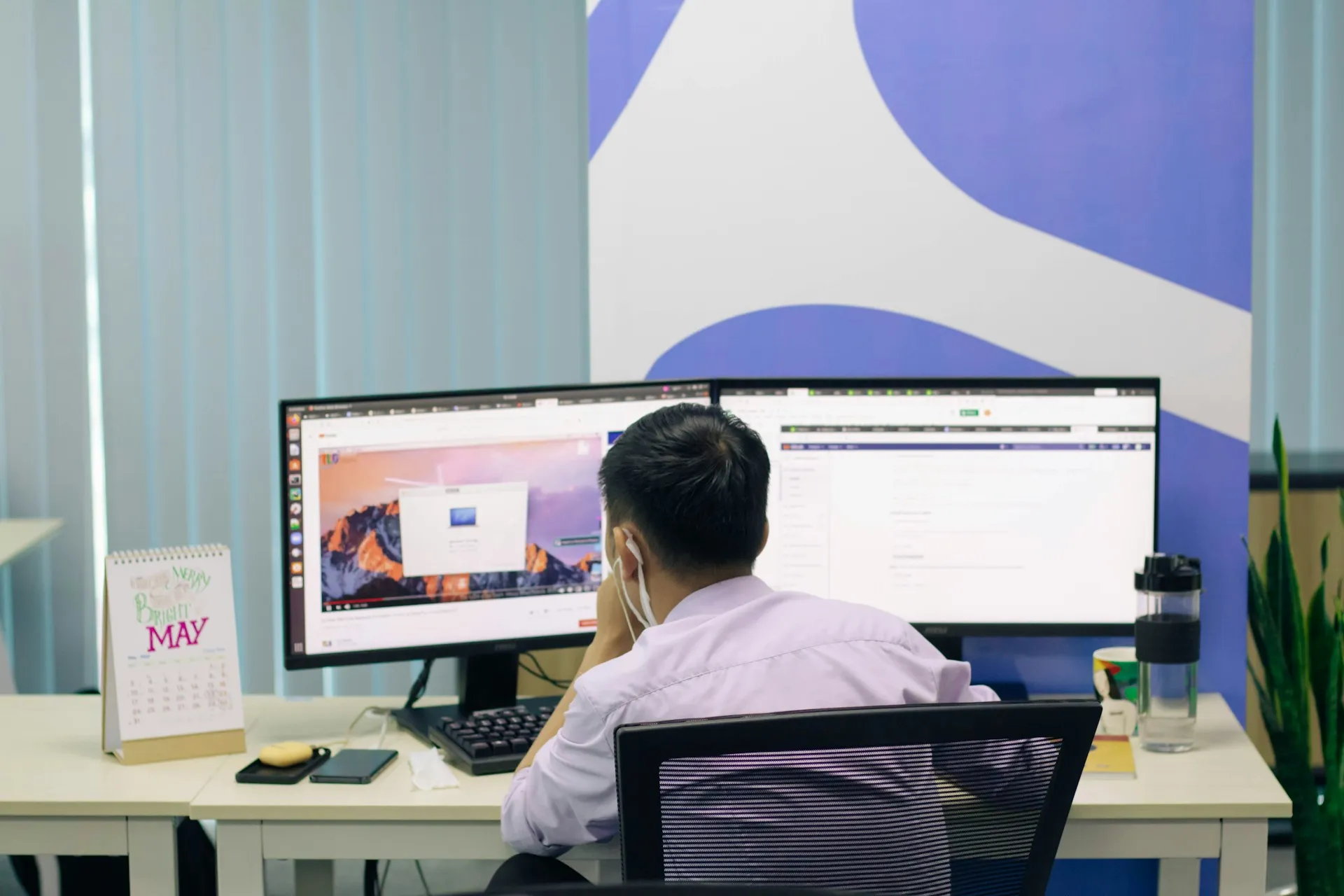 Professional working at a dual-monitor setup in a modern office