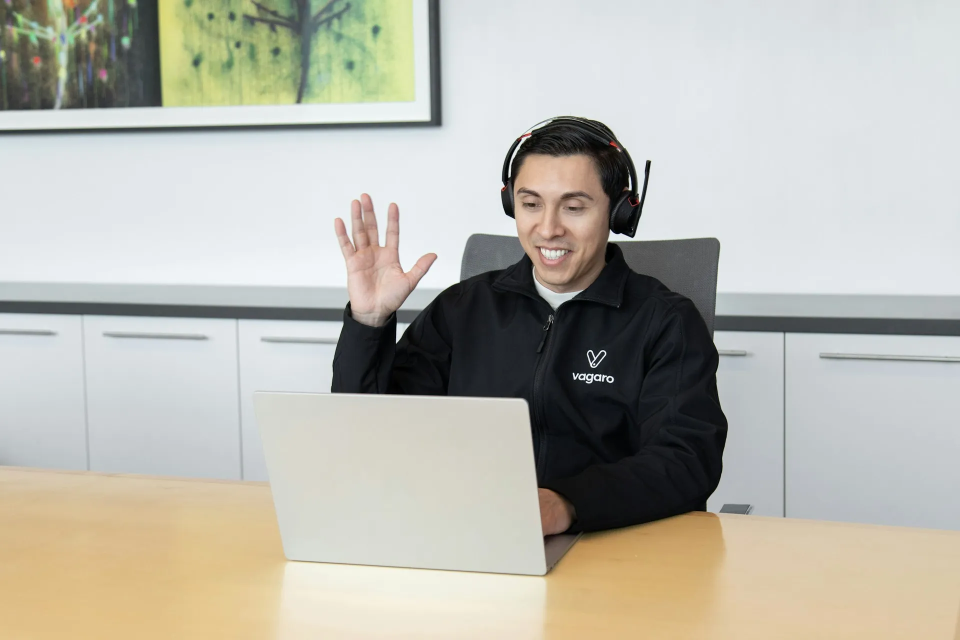 A customer support professional communicating online using a headset and laptop