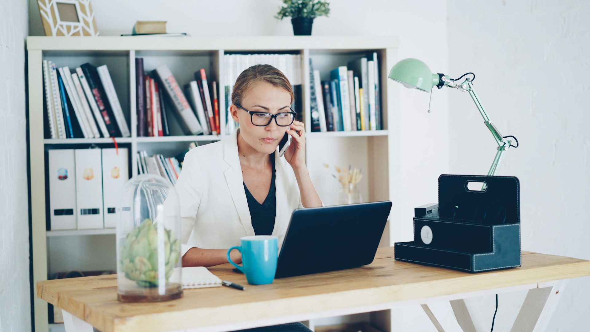 A confident young woman talking on a mobile phone in a modern office setting