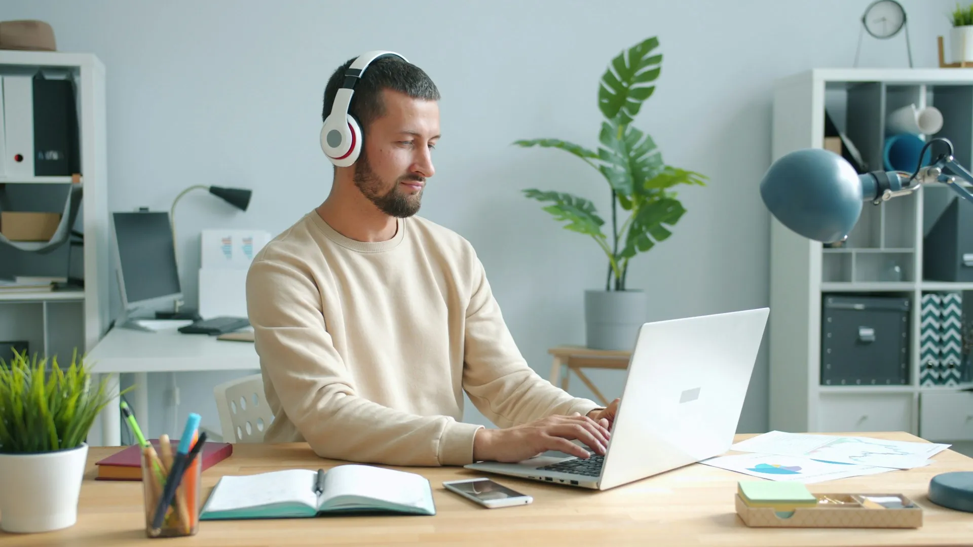 Professional wearing headphones working on a laptop in a modern office